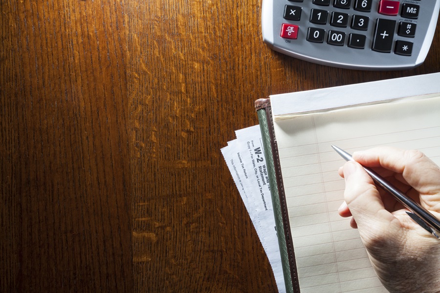 A note pad, a calculator, a W2 form on a desk