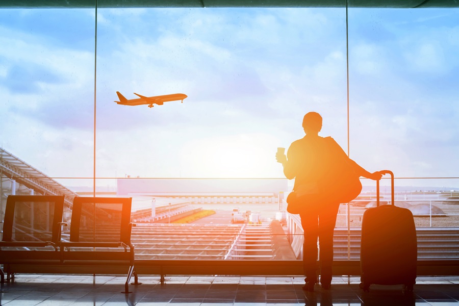 Image of a person at the airport looking out a window at an airplane